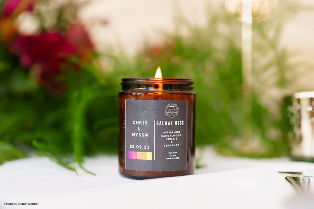 A personalised candle labeled 'Chris & Nyssa, 23.09.23' sits on a wedding table as part of the decor, its warm glow contributing to the intimate and magical ambiance of Hilltop's winter setting